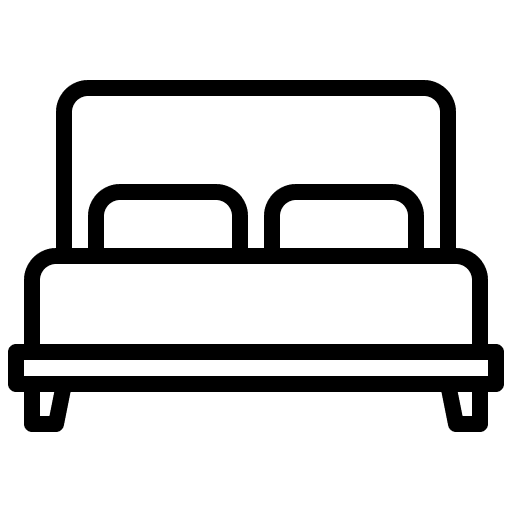 A person wearing a helmet rides a bicycle on a path surrounded by lush green trees, with a clear sky above.