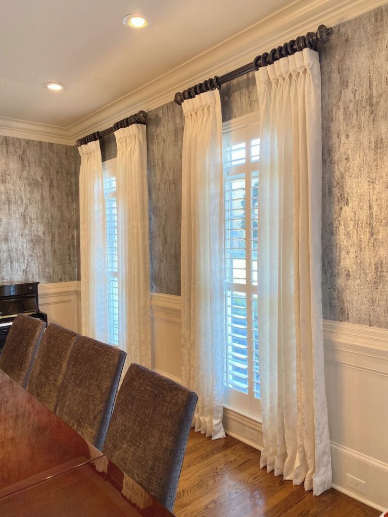 White pinch-pleat drapery layered over plantation shutters in a Chattanooga dining room
